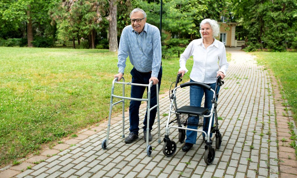 Two middle-aged people using a standard walker and a roller walker